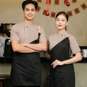 Đồng phục cửa hàng thực phẩm, siêu thị mini áo be tạp dề đen chéo độc đáo, form Slim Fit, vải LON USA Cotton 65/35 %